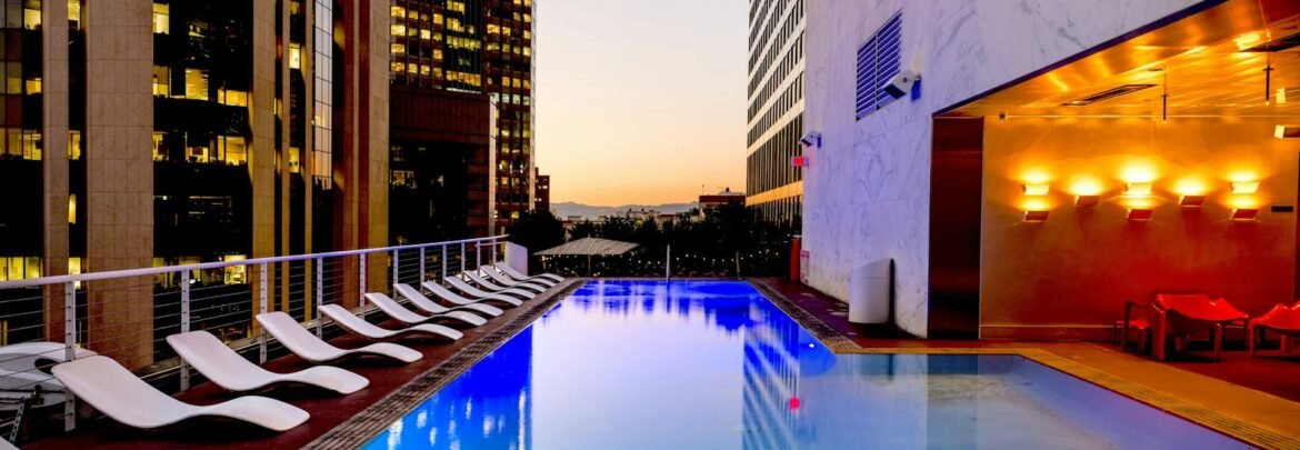Elegant rooftop pool with cityscape backdrop at sunset, reflecting urban luxury.