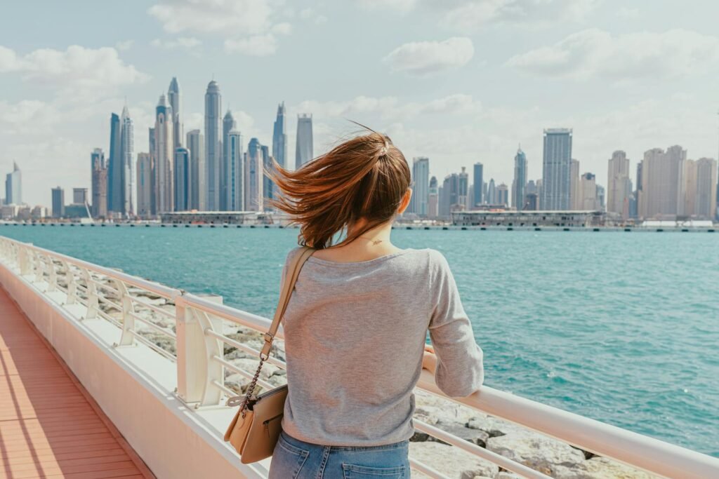 Woman gazes at Dubai Marina's modern skyline from a waterfront promenade.