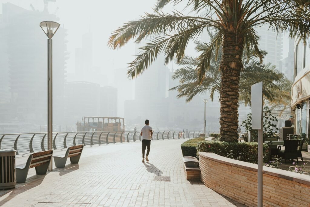 A man walking down a sidewalk next to palm trees