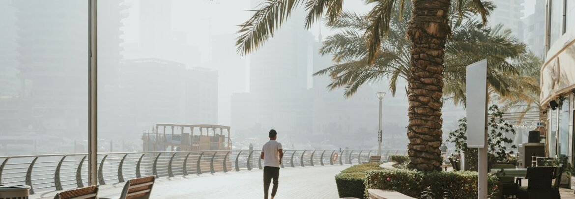 A man walking down a sidewalk next to palm trees