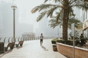 A man walking down a sidewalk next to palm trees