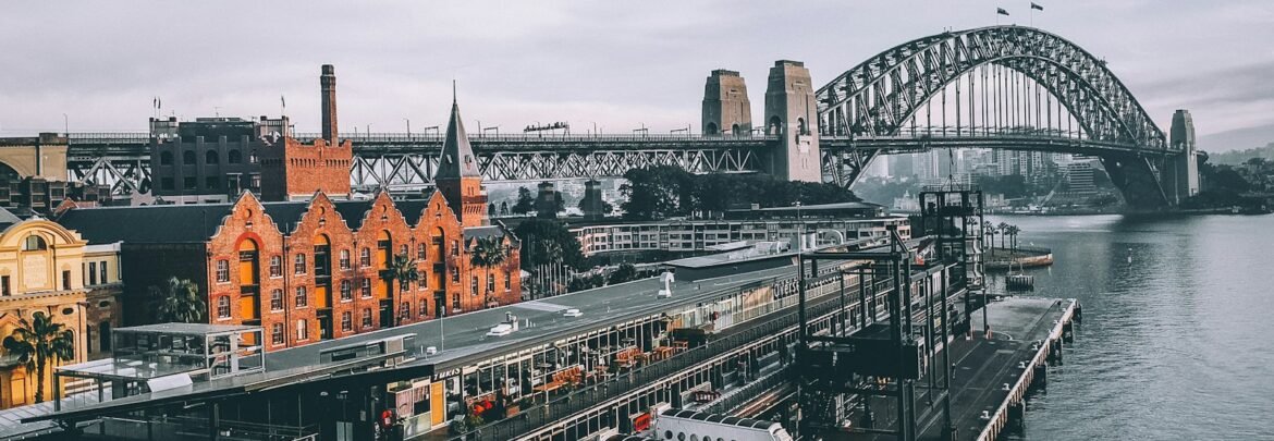 aerial photography of concrete buildings and bridge beside ocean under cloudy sky