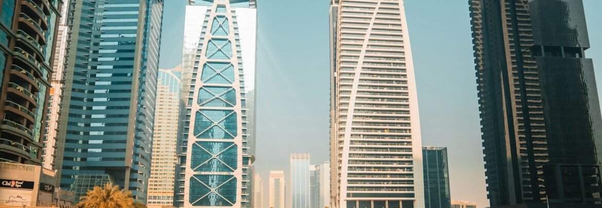 Modern skyscrapers reflect on the water in a city.