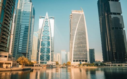 Modern skyscrapers reflect on the water in a city.