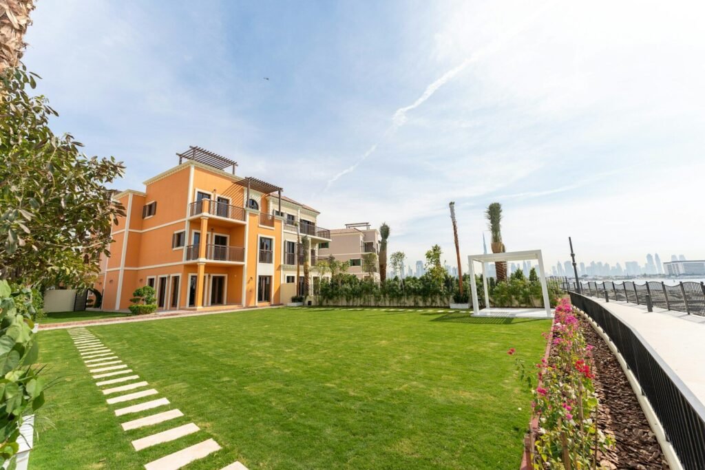 A luxurious building sits beside a vibrant green lawn.
