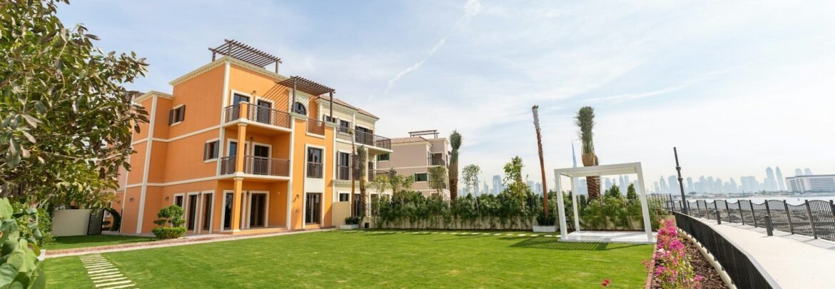 A luxurious building sits beside a vibrant green lawn.