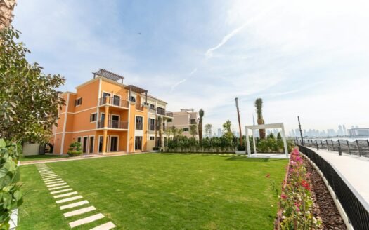 A luxurious building sits beside a vibrant green lawn.