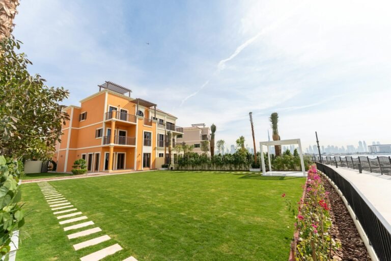 A luxurious building sits beside a vibrant green lawn.