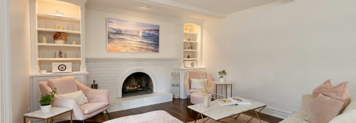A cozy living room with white walls and fireplace.
