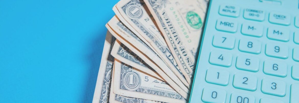 Us dollar bills and a calculator on blue background